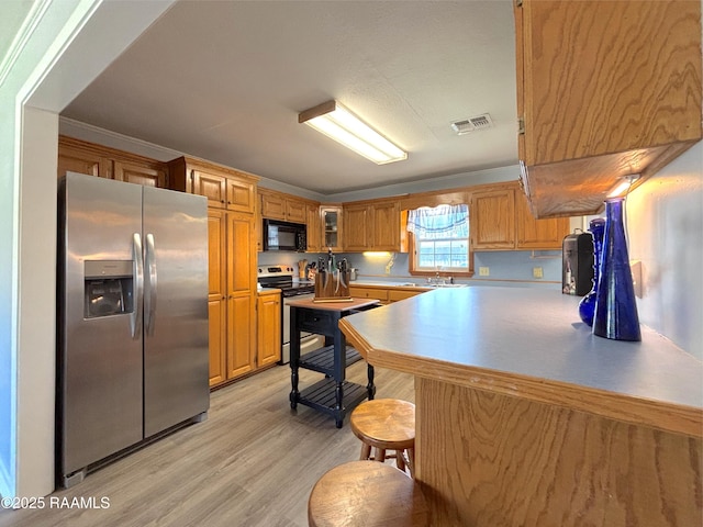 230 Glenwood Ave, Morgan City, LA 70380 - kitchen with appliances with stainless steel finishes, light wood-type flooring, glass insert cabinets, and brown cabinetry