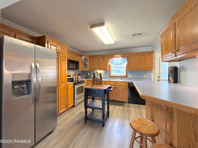 230 Glenwood Ave, Morgan City, LA 70380 - kitchen with black appliances, light wood finished floors, crown molding, light countertops, and a sink