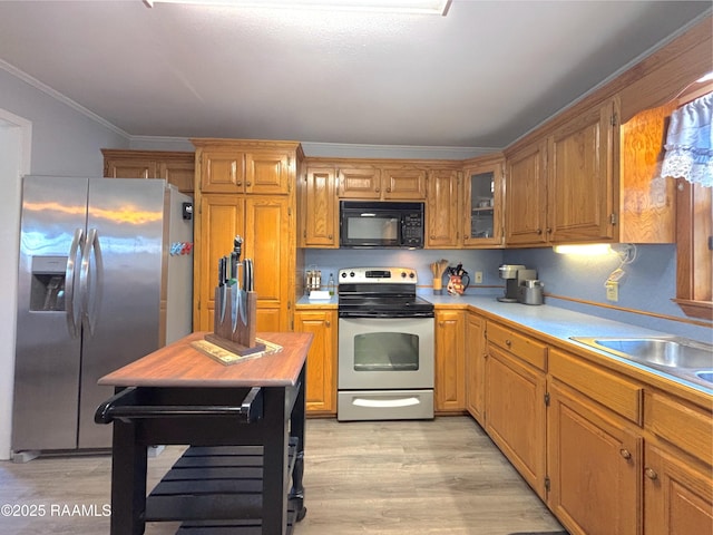 230 Glenwood Ave, Morgan City, LA 70380 - kitchen featuring stainless steel appliances, light wood-style floors, light countertops, ornamental molding, and a sink