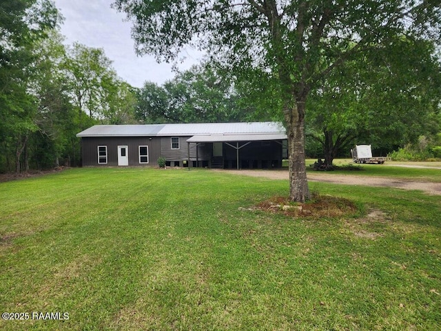 ranch-style home featuring driveway, a front lawn, metal roof, and a carport