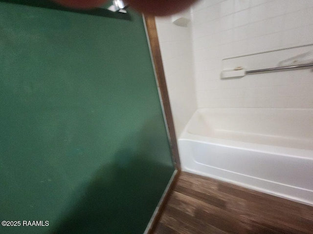bathroom with walk in shower, a washtub, baseboards, and wood finished floors