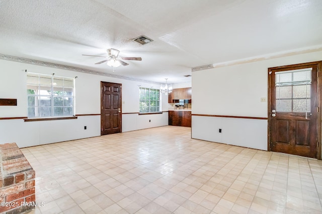 interior space featuring visible vents, a textured ceiling, and ceiling fan with notable chandelier