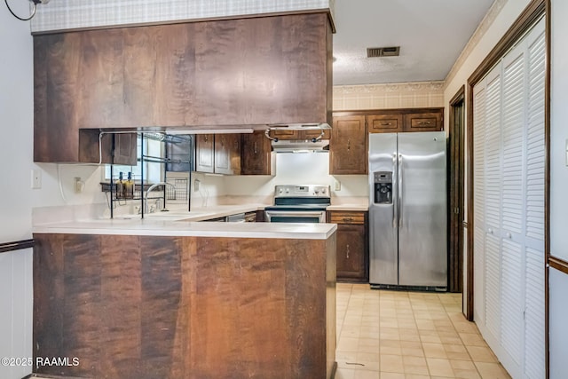 kitchen featuring a peninsula, stainless steel appliances, light countertops, and visible vents