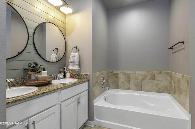 bathroom with a garden tub, double vanity, and a sink