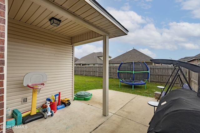 view of patio with a trampoline, grilling area, and a fenced backyard