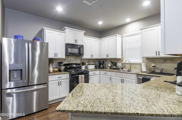 kitchen featuring a sink, light stone countertops, white cabinetry, and black appliances