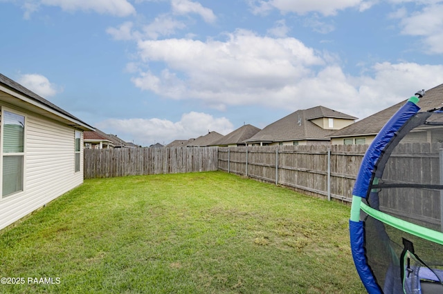 view of yard featuring a trampoline and a fenced backyard