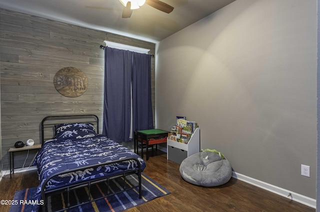 bedroom featuring wood walls, wood finished floors, vaulted ceiling, ceiling fan, and baseboards