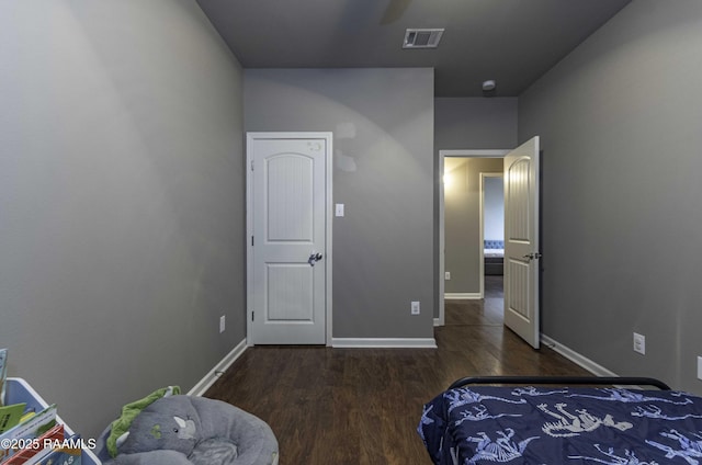 bedroom with baseboards, visible vents, and wood finished floors
