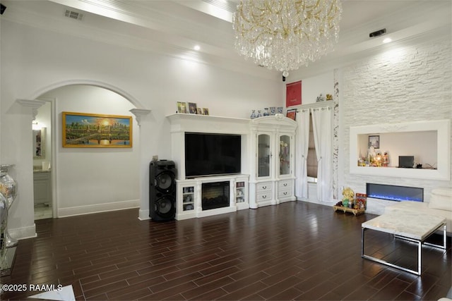 living room featuring a glass covered fireplace, ornamental molding, a chandelier, wood finished floors, and baseboards
