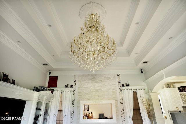detailed view of a chandelier, crown molding, and a raised ceiling