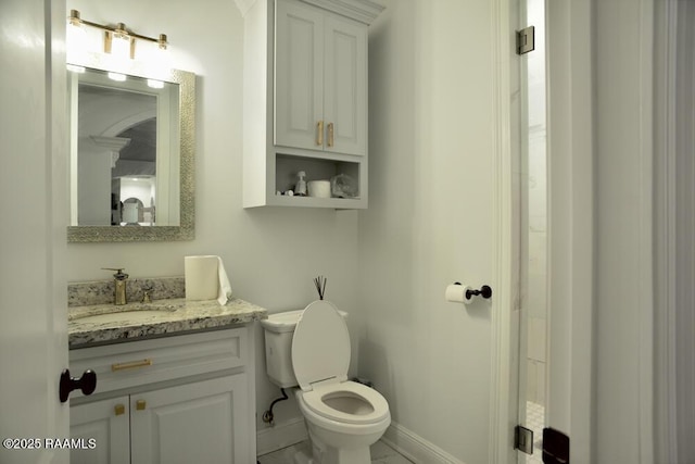 bathroom with toilet, vanity, and baseboards