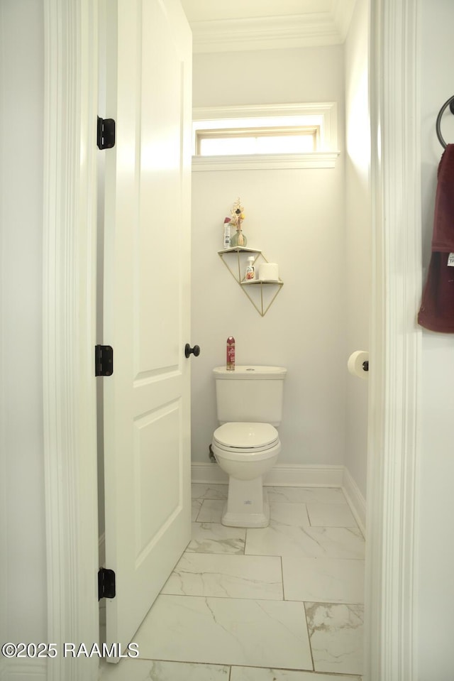 bathroom with marble look tiles, toilet, ornamental molding, and baseboards