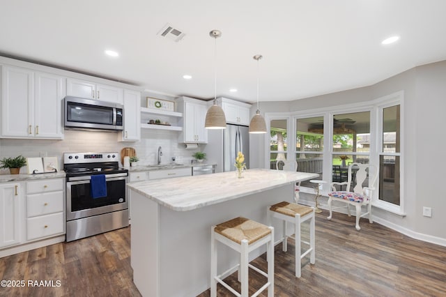 513 Emmeline St, New Iberia, LA 70563 - kitchen with appliances with stainless steel finishes, a breakfast bar, open shelves, white cabinets, and dark wood-style flooring