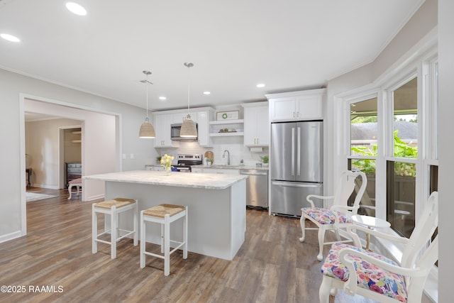 513 Emmeline St, New Iberia, LA 70563 - kitchen featuring appliances with stainless steel finishes, exhaust hood, a center island, white cabinets, and wood finished floors