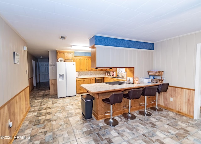 2405 S Chataignier Rd, Ville Platte, LA 70586 - kitchen with white refrigerator with ice dispenser, a sink, a peninsula, wood walls, and light countertops