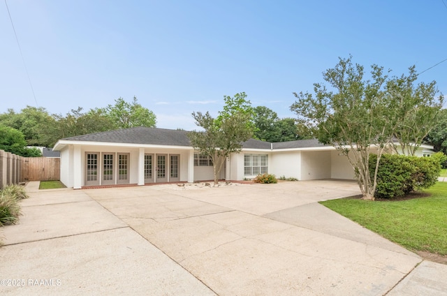 ranch-style house with french doors, driveway, fence, and stucco siding