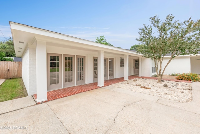 view of front of house featuring fence, brick siding, and a patio