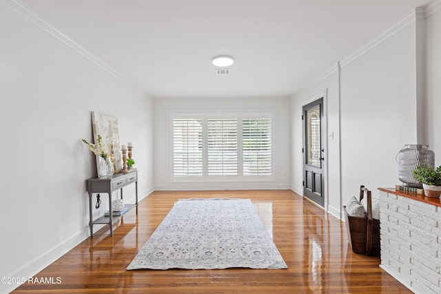 entryway featuring wood finished floors, baseboards, and crown molding
