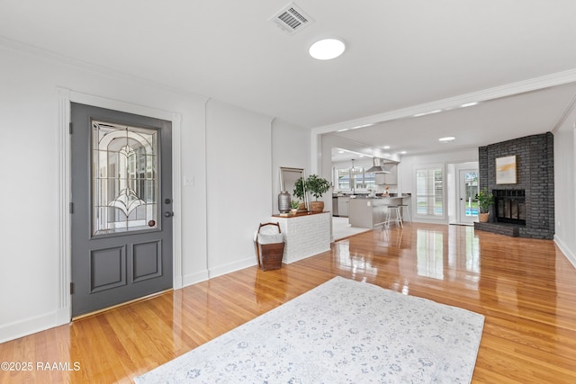 foyer featuring wood finished floors, crown molding, a fireplace, and baseboards