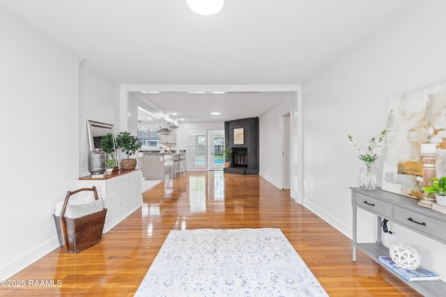 hallway with light wood-style floors, baseboards, and ornamental molding