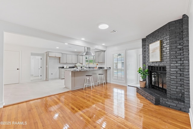 living room featuring light wood finished floors, a fireplace, crown molding, and baseboards