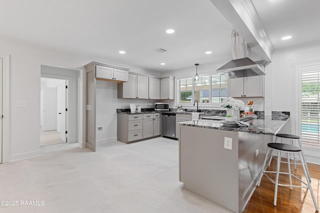 kitchen featuring stainless steel appliances, crown molding, a peninsula, wall chimney range hood, and dark stone counters