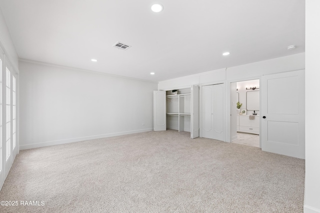 unfurnished bedroom featuring recessed lighting, carpet, two closets, ornamental molding, and baseboards