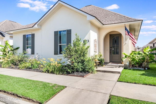 123 Laurel Grove Blvd, Youngsville, LA 70592 - view of front of property featuring roof with shingles, stucco siding, and a front lawn