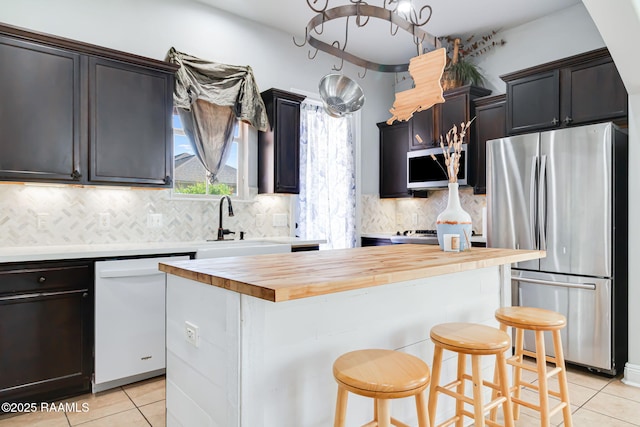 123 Laurel Grove Blvd, Youngsville, LA 70592 - kitchen featuring stainless steel appliances, wood counters, light tile patterned floors, and a center island
