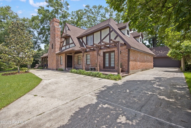 207 Beverly Dr, Lafayette, LA 70503 - tudor house featuring french doors, brick siding, a shingled roof, concrete driveway, and a chimney