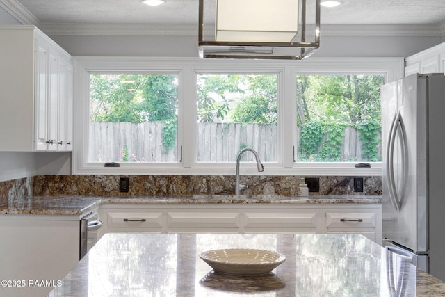 207 Beverly Dr, Lafayette, LA 70503 - kitchen with freestanding refrigerator, white cabinets, light stone counters, and crown molding