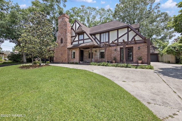 207 Beverly Dr, Lafayette, LA 70503 - tudor house featuring brick siding, a chimney, a front lawn, driveway, and stucco siding