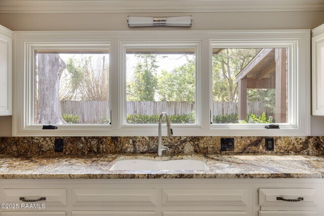 207 Beverly Dr, Lafayette, LA 70503 - kitchen view of a sink, light stone counters, and white cabinetry