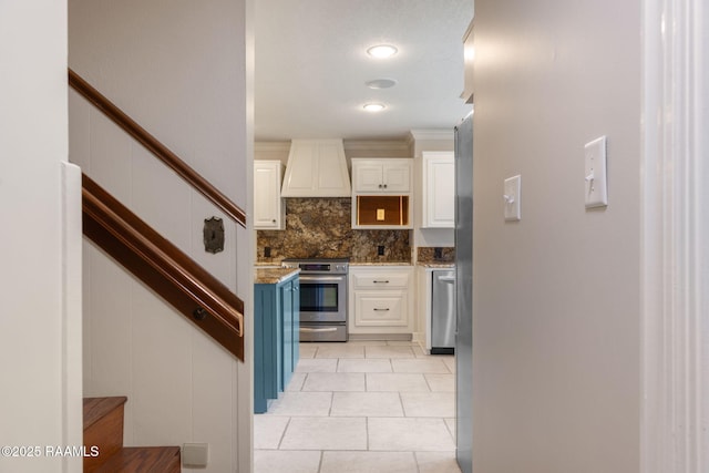 207 Beverly Dr, Lafayette, LA 70503 - kitchen with stainless steel appliances, custom range hood, white cabinets, backsplash, and light tile patterned flooring