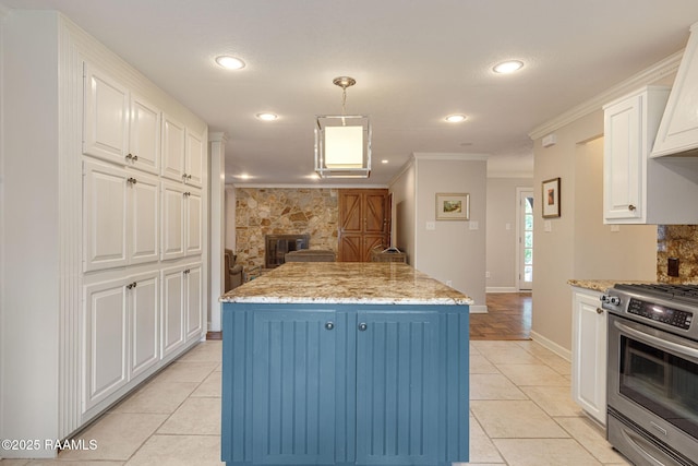 207 Beverly Dr, Lafayette, LA 70503 - kitchen with stainless steel gas range, white cabinetry, light tile patterned floors, crown molding, and a kitchen island