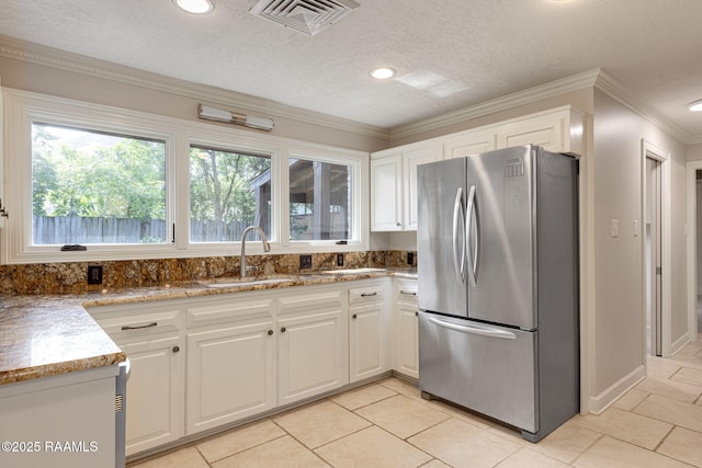 207 Beverly Dr, Lafayette, LA 70503 - kitchen featuring freestanding refrigerator, a sink, white cabinetry, ornamental molding, and light stone counters