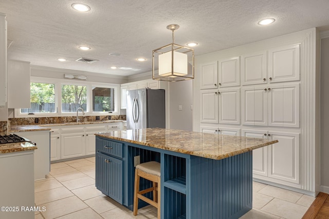 207 Beverly Dr, Lafayette, LA 70503 - kitchen with freestanding refrigerator, white cabinetry, a center island, light tile patterned floors, and a textured ceiling