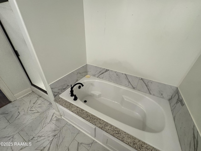 full bath featuring a garden tub and marble finish floors
