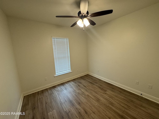 empty room with dark wood finished floors, a ceiling fan, and baseboards