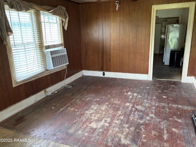 empty room featuring wood walls, hardwood / wood-style flooring, cooling unit, and baseboards