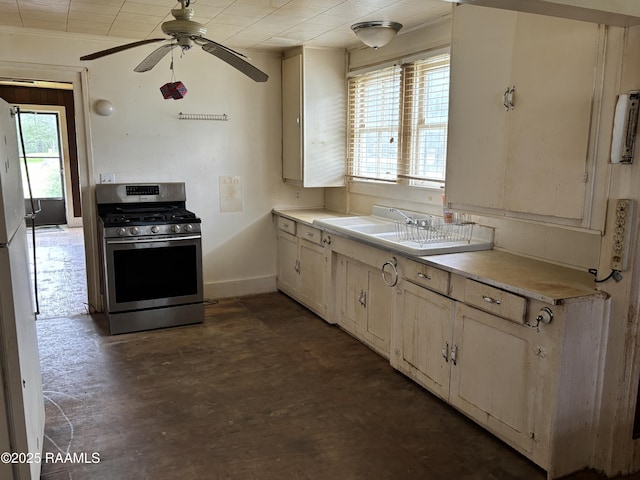 kitchen featuring gas range, ceiling fan, light countertops, and baseboards