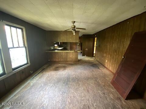 736 N Court St, Opelousas, LA 70570 - unfurnished living room with plenty of natural light, wooden walls, and ceiling fan