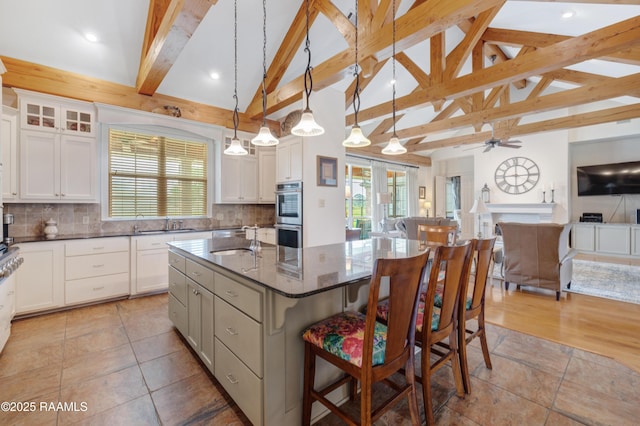 2311 Vida Shaw Rd, New Iberia, LA 70563 - kitchen with open floor plan, an island with sink, a ceiling fan, a kitchen bar, and beamed ceiling