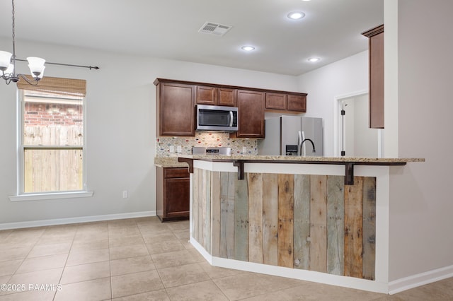 223 Moss Bluff Dr, Lafayette, LA 70507 - kitchen featuring appliances with stainless steel finishes, a chandelier, light stone counters, baseboards, and tasteful backsplash
