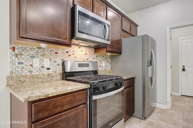 223 Moss Bluff Dr, Lafayette, LA 70507 - kitchen with stainless steel appliances, light tile patterned floors, tasteful backsplash, light stone countertops, and dark brown cabinetry
