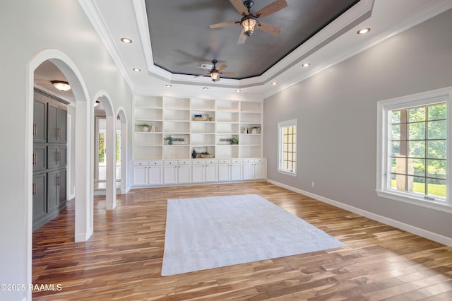 807 Cambridge Dr Res, Unit Res, Lafayette, LA 70503 - empty room with arched walkways, a tray ceiling, light wood-style flooring, crown molding, and built in features