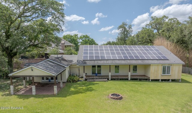 807 Cambridge Dr Res, Unit Res, Lafayette, LA 70503 - rear view of property with a lawn, roof mounted solar panels, a patio area, and a fire pit