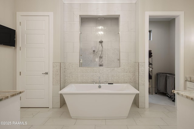 137 Grandview Terrace Dr, Youngsville, LA 70592 - bathroom featuring marble finish flooring, a freestanding bath, a tile shower, vanity, and tile walls