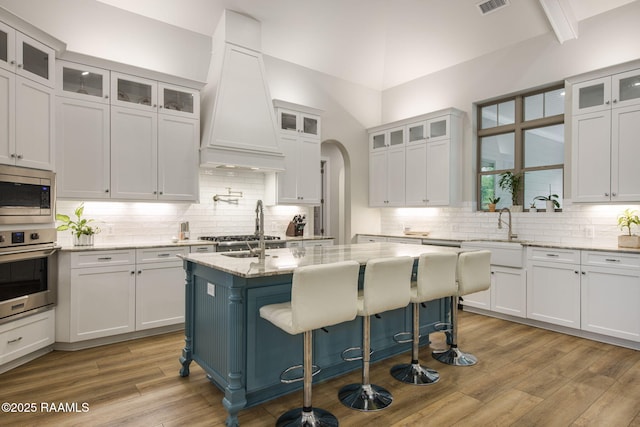 137 Grandview Terrace Dr, Youngsville, LA 70592 - kitchen featuring appliances with stainless steel finishes, a sink, custom exhaust hood, white cabinetry, and lofted ceiling